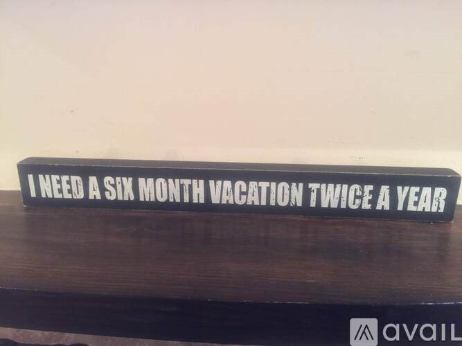 A sign that says "I need a six month vacation twice a year" is displayed on a wooden surface.