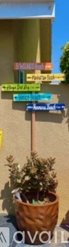 A brown planter with a green plant in front of a building with a sign.