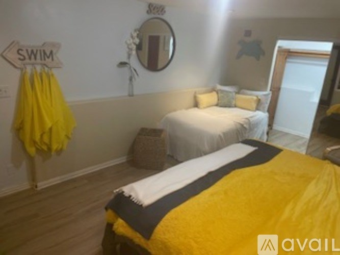 A bedroom with a white bed and a yellow towel hanging on the wall.