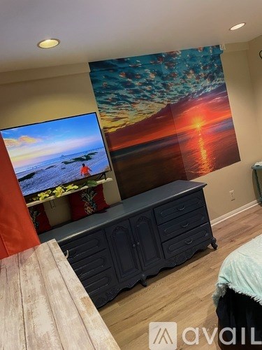 A bedroom with a large painting on the wall and a TV screen showing a beach scene.