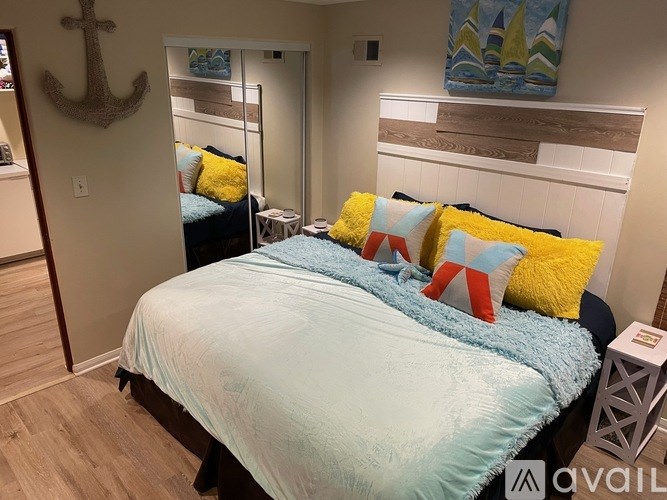 A bedroom with a bed, a mirror, and a painting on the wall.