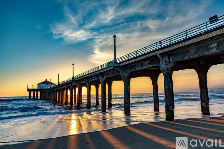A pier extends into the ocean at sunset.