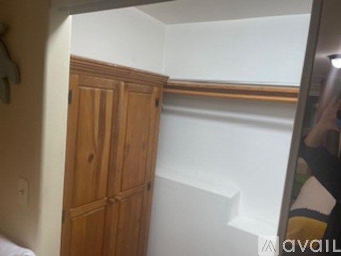 A wooden wardrobe is in a corner of a room.