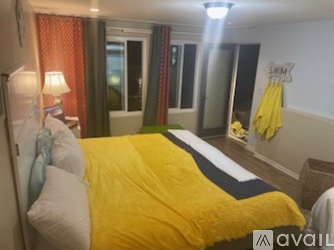 A bedroom with a yellow bedspread and a sign that says "SWIM" on the wall.