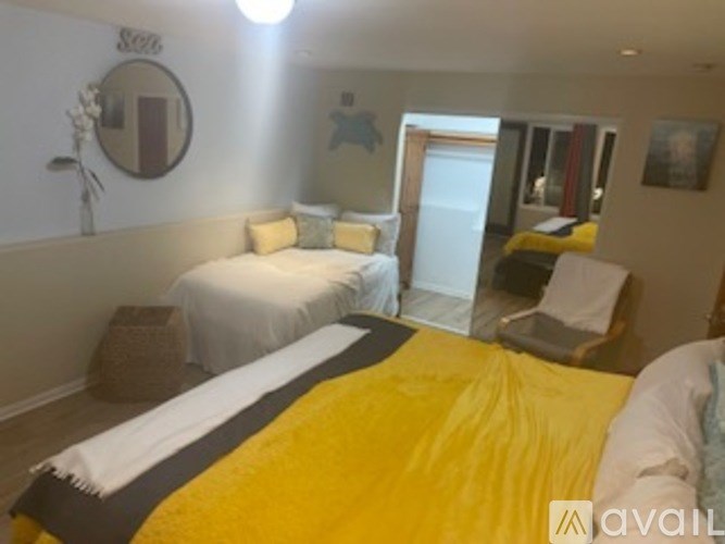 A bedroom with a white bed and a yellow bedspread.