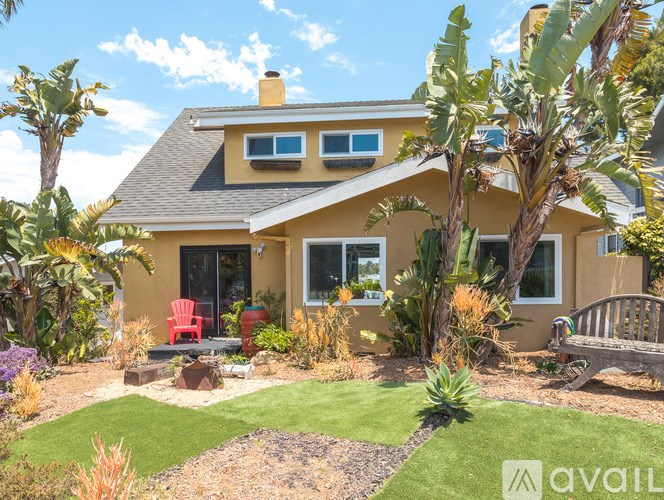 A house with a yellow exterior and a red chair in front of it.