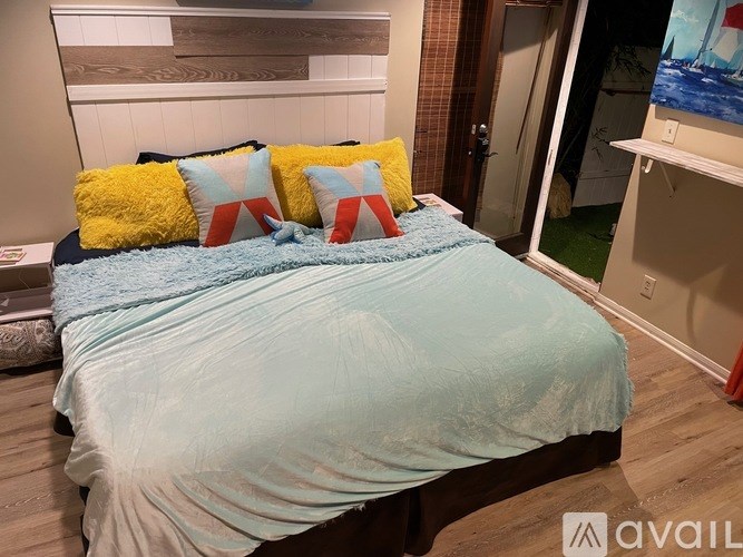 A bed with a blue comforter and pillows with a red, white, and blue design.