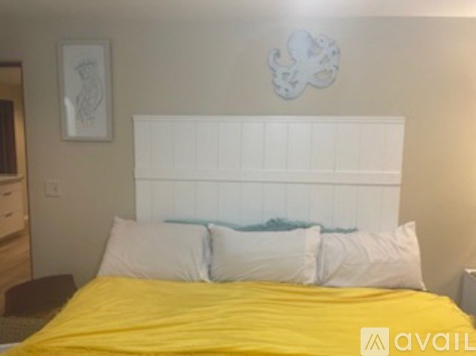 A bed with a white headboard and a yellow comforter.