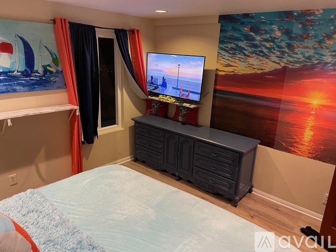 A bedroom with a bed, a television, and a painting on the wall.