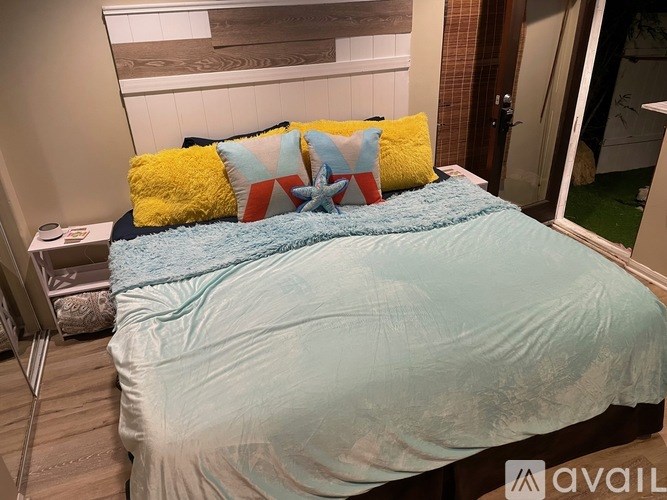 A bed with a blue comforter and a yellow pillow with a star design on it.
