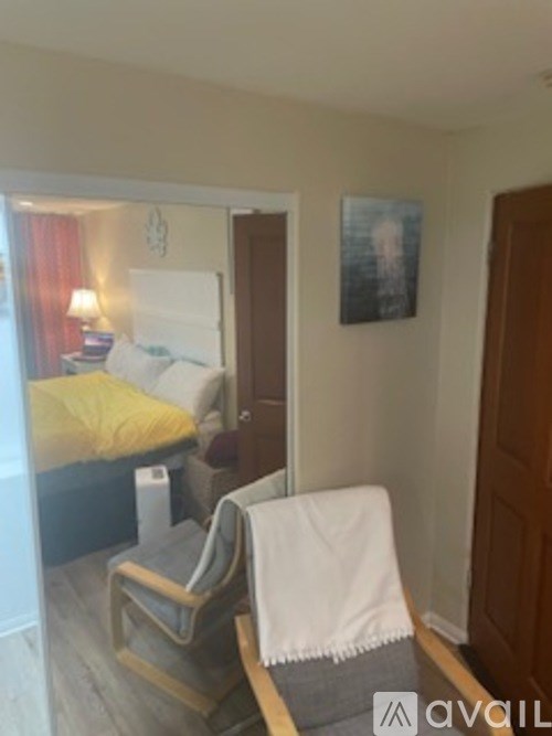 A bedroom with a bed, chair, and a picture on the wall.