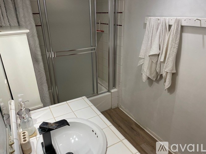 A bathroom with a white sink and a glass shower door.