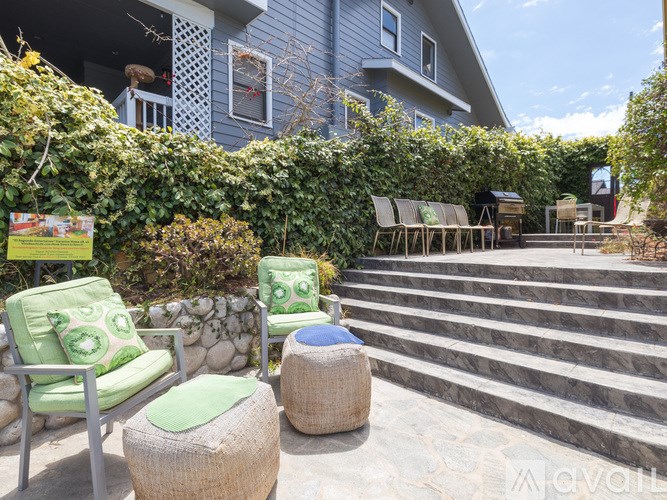 A patio with a green chair and a woven ottoman.