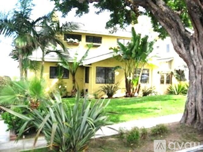 A yellow house with a tree in front.