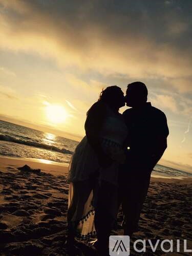 A couple is standing on the beach during sunset.