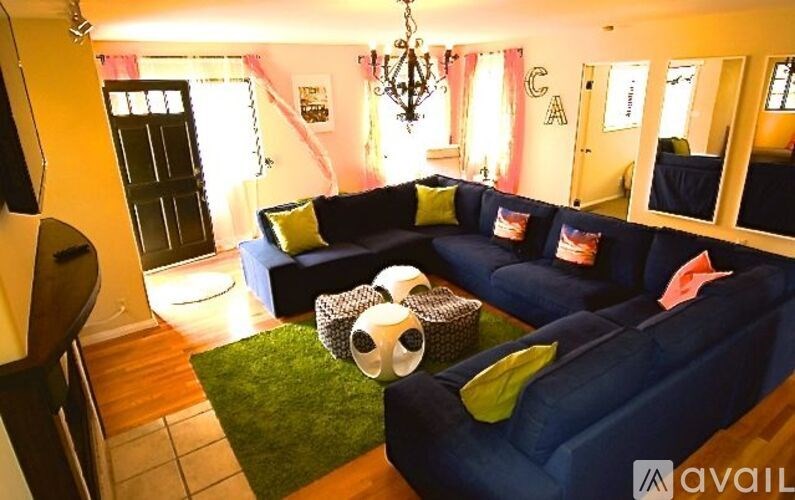 A living room with a blue couch and a green rug.