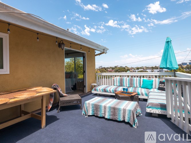 A sunny day at the beach with a blue umbrella and striped cushions on the deck.