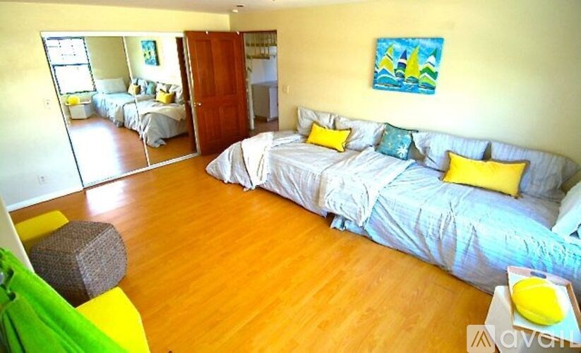 A bedroom with a bed and a couch with a painting on the wall.