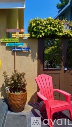 A red chair sits on a patio in front of a house.