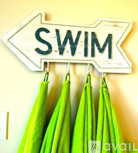 A sign that says "swim" with three green umbrellas hanging below it.