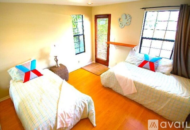 Two twin beds with pillows and a clock on the wall.