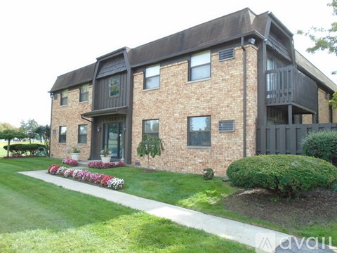 A brick house with a balcony and a garden in front.
