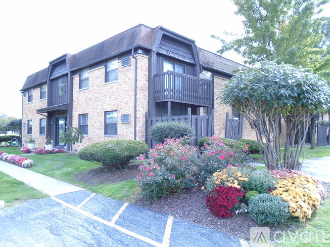 A brick building with a balcony and a small garden in front.