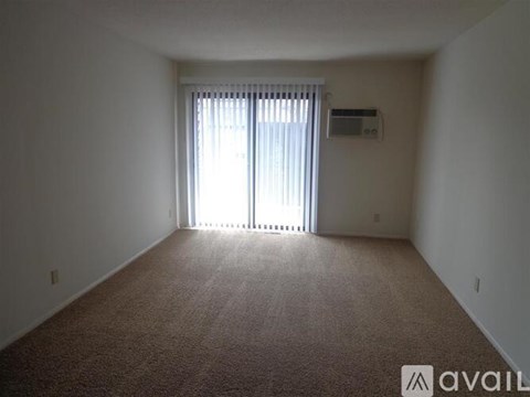 A carpeted room with a window and blinds.