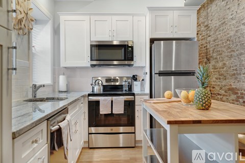 A kitchen with white cabinets and a wooden island.