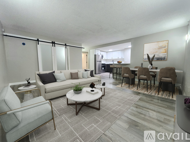 A living room with a grey sofa, a white coffee table, and a dining table with chairs.