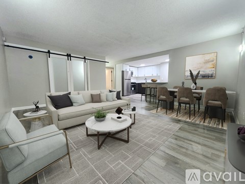 A living room with a grey sofa, a white coffee table, and a dining table with chairs.