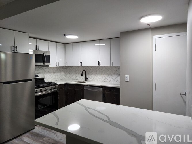A modern kitchen with a stainless steel refrigerator and a marble countertop.