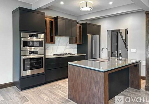 A modern kitchen with dark wood cabinets and stainless steel appliances.