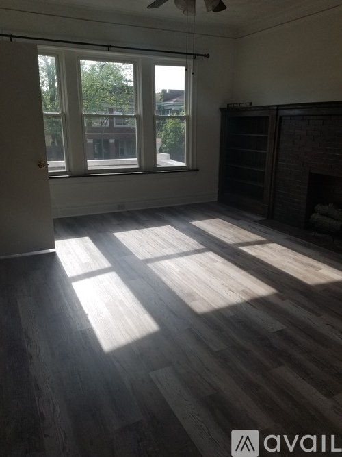A room with wooden flooring and a window with curtains.