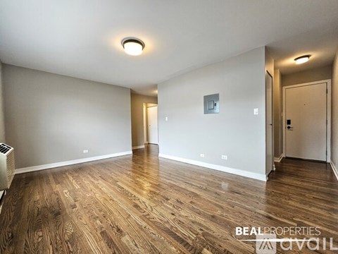 A spacious room with wooden flooring and white walls.