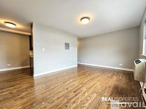 A spacious room with wooden flooring and a sliding door.