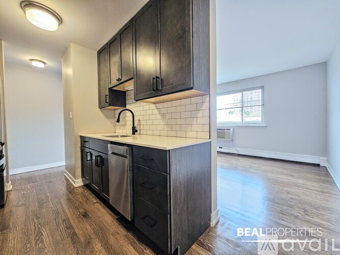 A kitchen with black cabinets and a white subway tile backsplash.