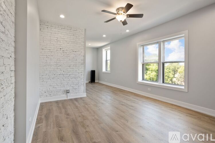 A spacious room with a ceiling fan and a window overlooking trees.