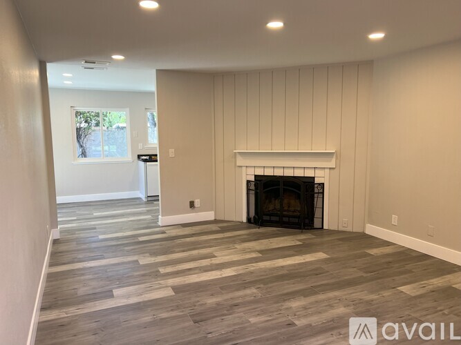 A living room with a fireplace and wood flooring.