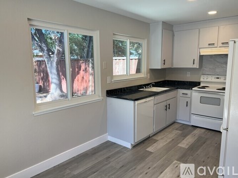 A kitchen with white cabinets and a black countertop.