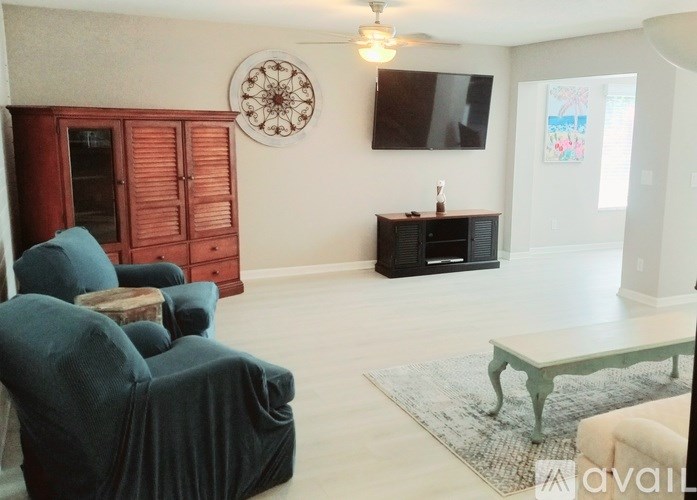 A living room with a green chair and a wooden cabinet.