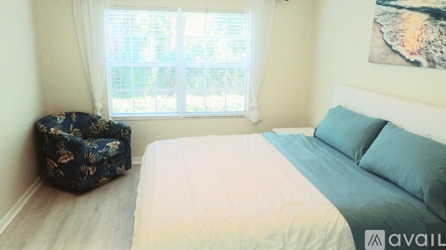 A bedroom with a large bed and a window with a view of trees.
