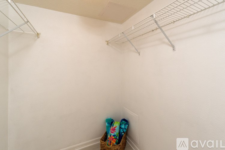 A small closet with a basket of items on the floor.