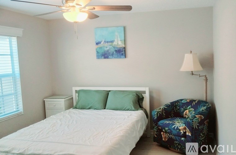 A bedroom with a bed, a chair, and a ceiling fan.