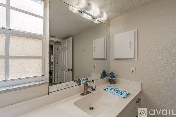 A bathroom with a large mirror, sink, and a window with blinds.