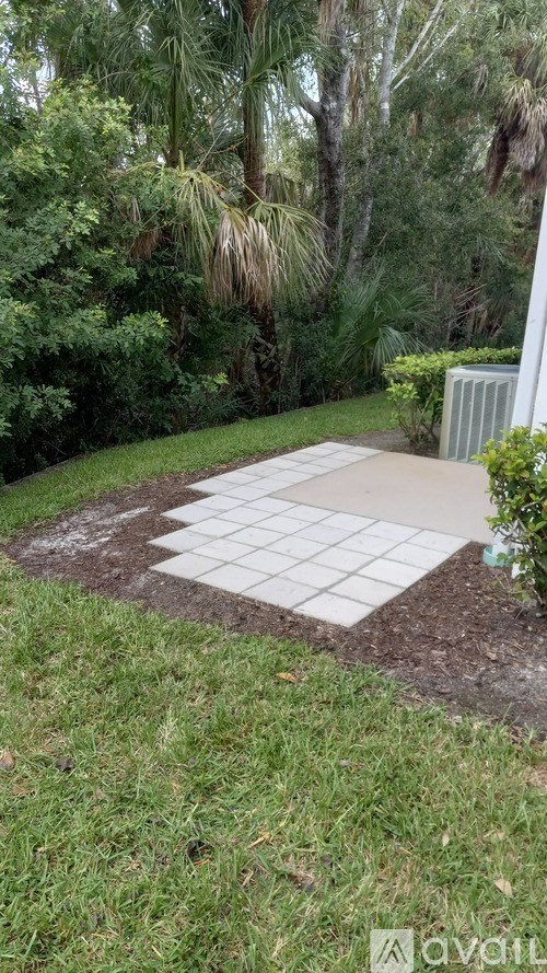 A garden with a white tile pathway leading to a white wall.