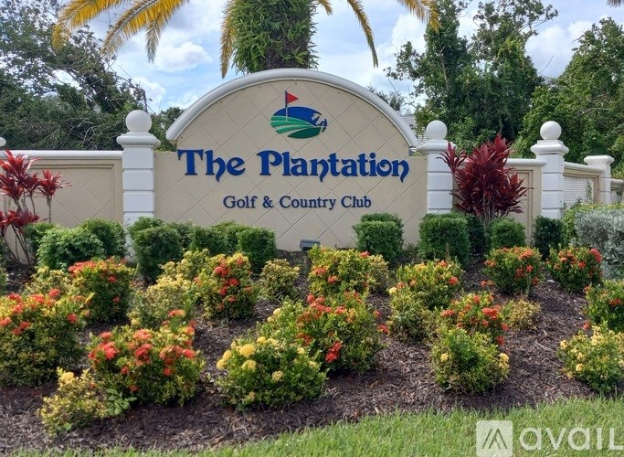 The Plantation Golf & Country Club sign is surrounded by colorful flowers.