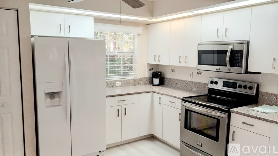 A kitchen with white cabinets and appliances.