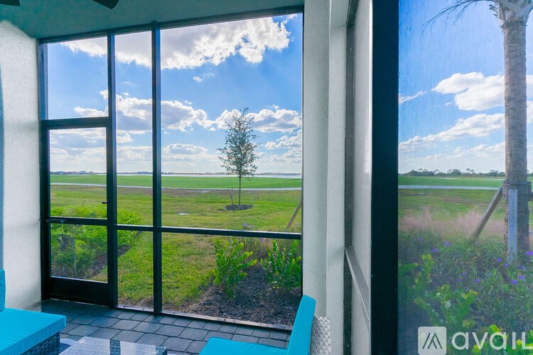 A room with a view of a tree and a field through the window.