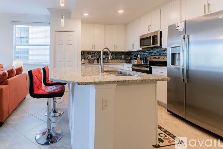 A kitchen with a bar stool and a refrigerator.